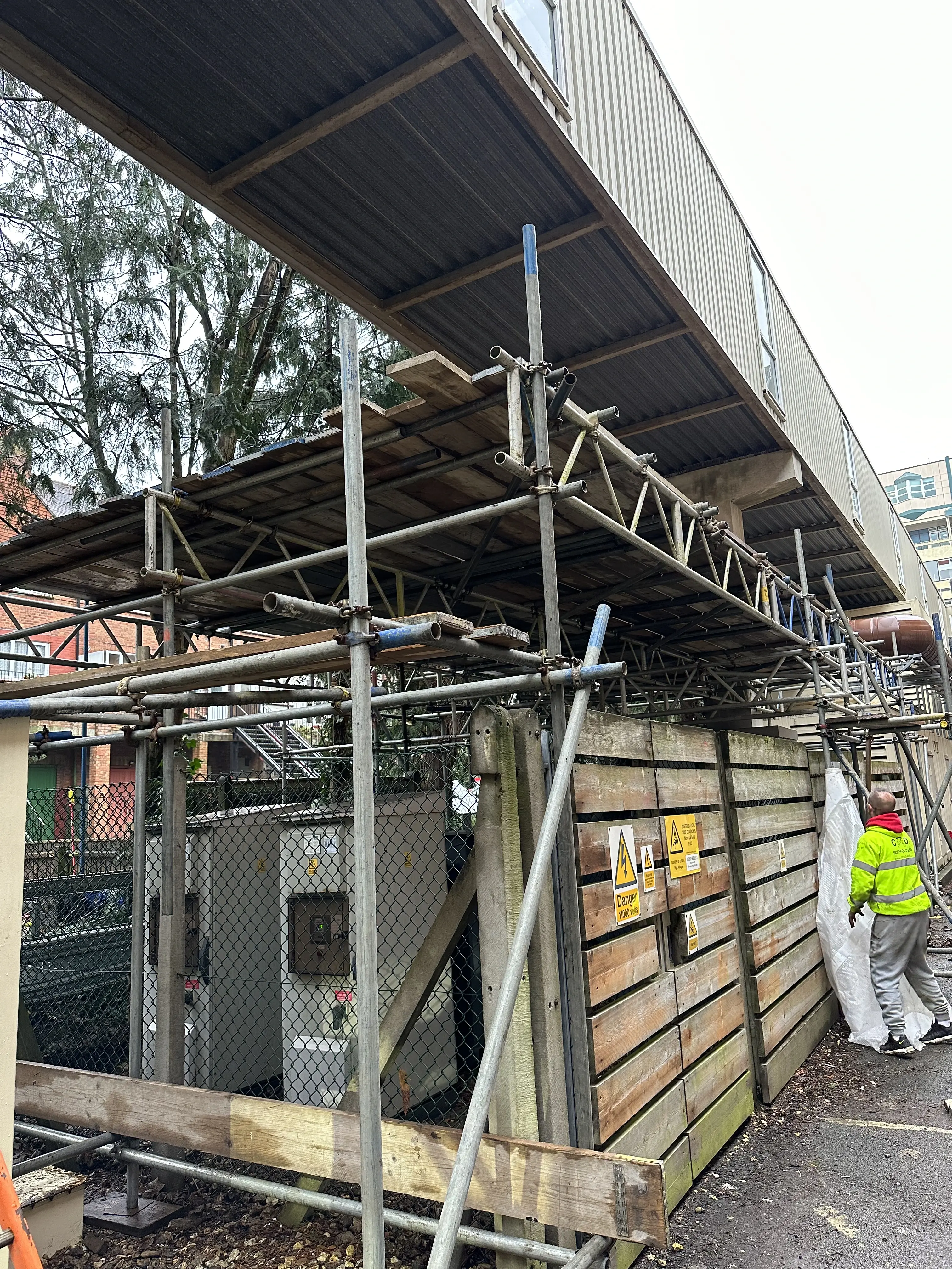 A man standing next to a building under construction.